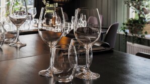 A dining table with several wine glasses and a vase of dried plants. - Hotell MAVI (Viken)
