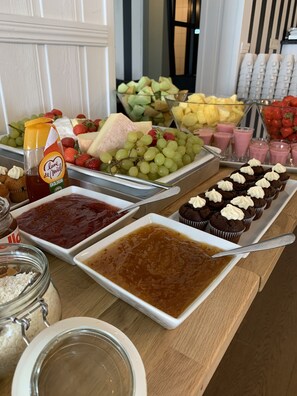 A buffet table with various food items including fruits, cheeses, and desserts. - Hotell MAVI (Viken)
