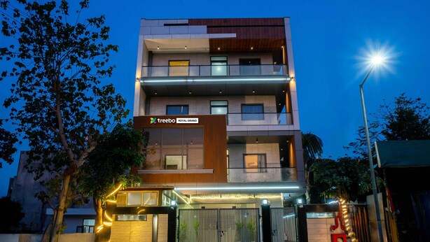 A multi-story hotel with a modern design, featuring a prominent entrance with a gated driveway and illuminated pathways. - Treebo Royal Grand, Sector 71 (Noida)
