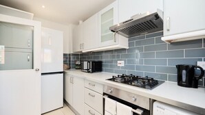 A modern kitchen with white cabinets, a gas stove, a microwave, and a dishwasher.