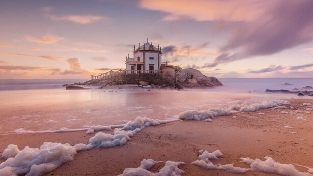 A coastal building with a staircase leading to a white structure, surrounded by a rocky shoreline and calm sea. - Miramar Terrace First Line Beach View Villa (Vila Nova de Gaia)