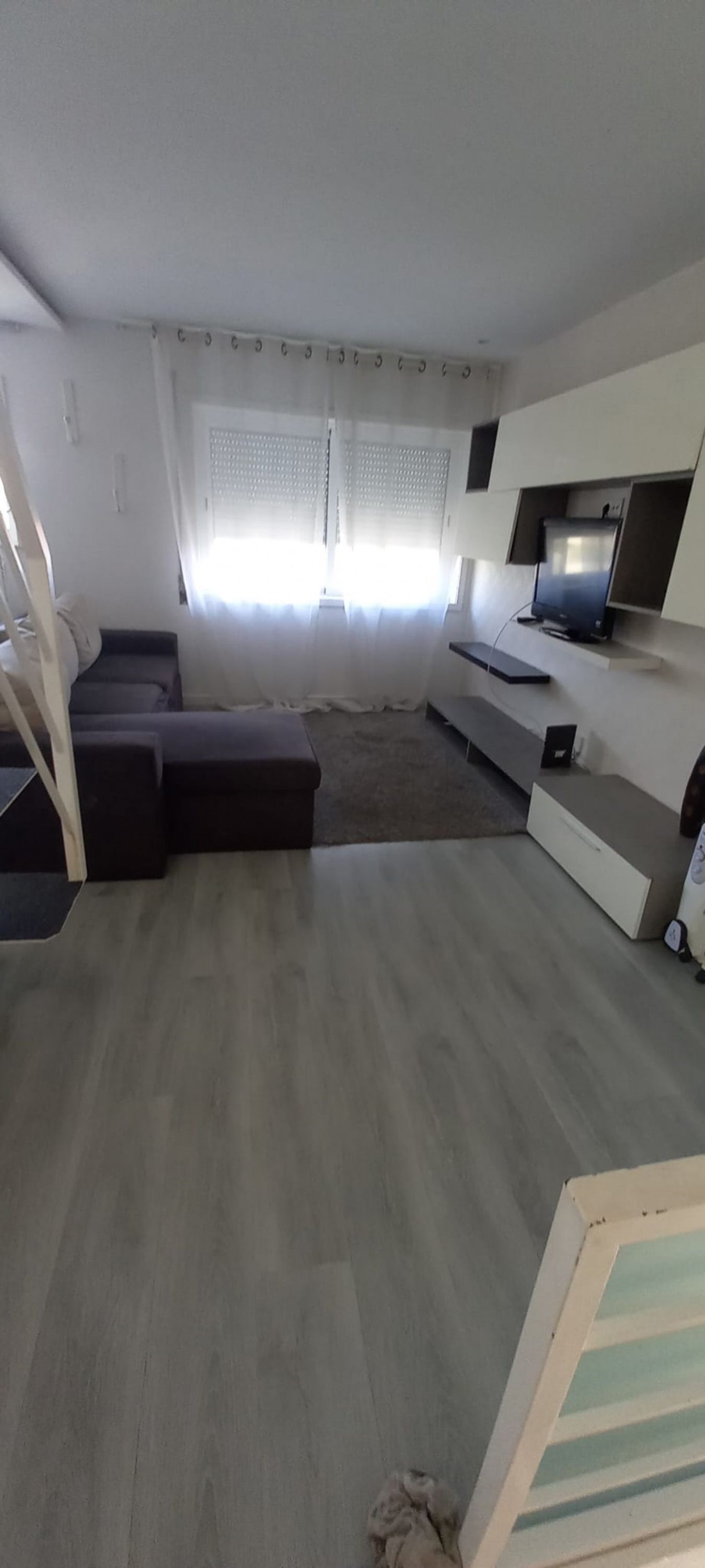 Una sala moderna con un sofá modular, un televisor de pantalla plana montado en la pared y una mesita.