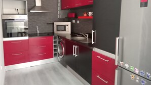 A modern kitchen with red and black cabinetry, stainless steel appliances, and a built-in microwave. - Miramar Terrace First Line Beach View Villa (Vila Nova de Gaia)