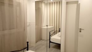 A bedroom with a bed, a bedside table, a mirror, and a door. - Miramar Terrace First Line Beach View Villa (Vila Nova de Gaia)