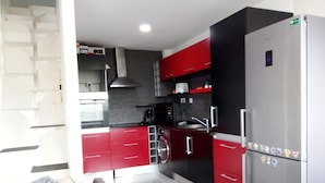 A modern kitchen with red and black cabinets, a stainless steel refrigerator, and a built-in oven. - Miramar Terrace First Line Beach View Villa (Vila Nova de Gaia)