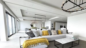 A modern living room with a sectional sofa, a coffee table, and a large window providing natural light. - Buddy's Bungalow (Nassau)