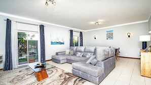A modern living room with a grey sectional sofa, a glass coffee table, and a patterned rug. - Algarve Charm with Private Pool, Garden & Spacious Area in Lagos (Lagos)