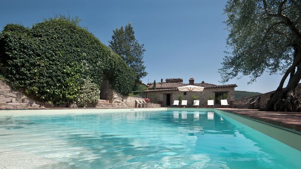 A clear swimming pool with a stone building in the background, surrounded by trees and a stone wall. - Farmhouse apartments with breathtaking scenery and unspoiled nature. (Umbria)