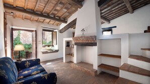 A spacious living room with a wooden ceiling, a blue sofa, a fireplace, and a staircase. - Farmhouse apartments with breathtaking scenery and unspoiled nature. (Umbria)