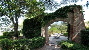 An arched brick structure covered with ivy, surrounded by gravel and greenery. - Farmhouse apartments with breathtaking scenery and unspoiled nature. (Umbria)