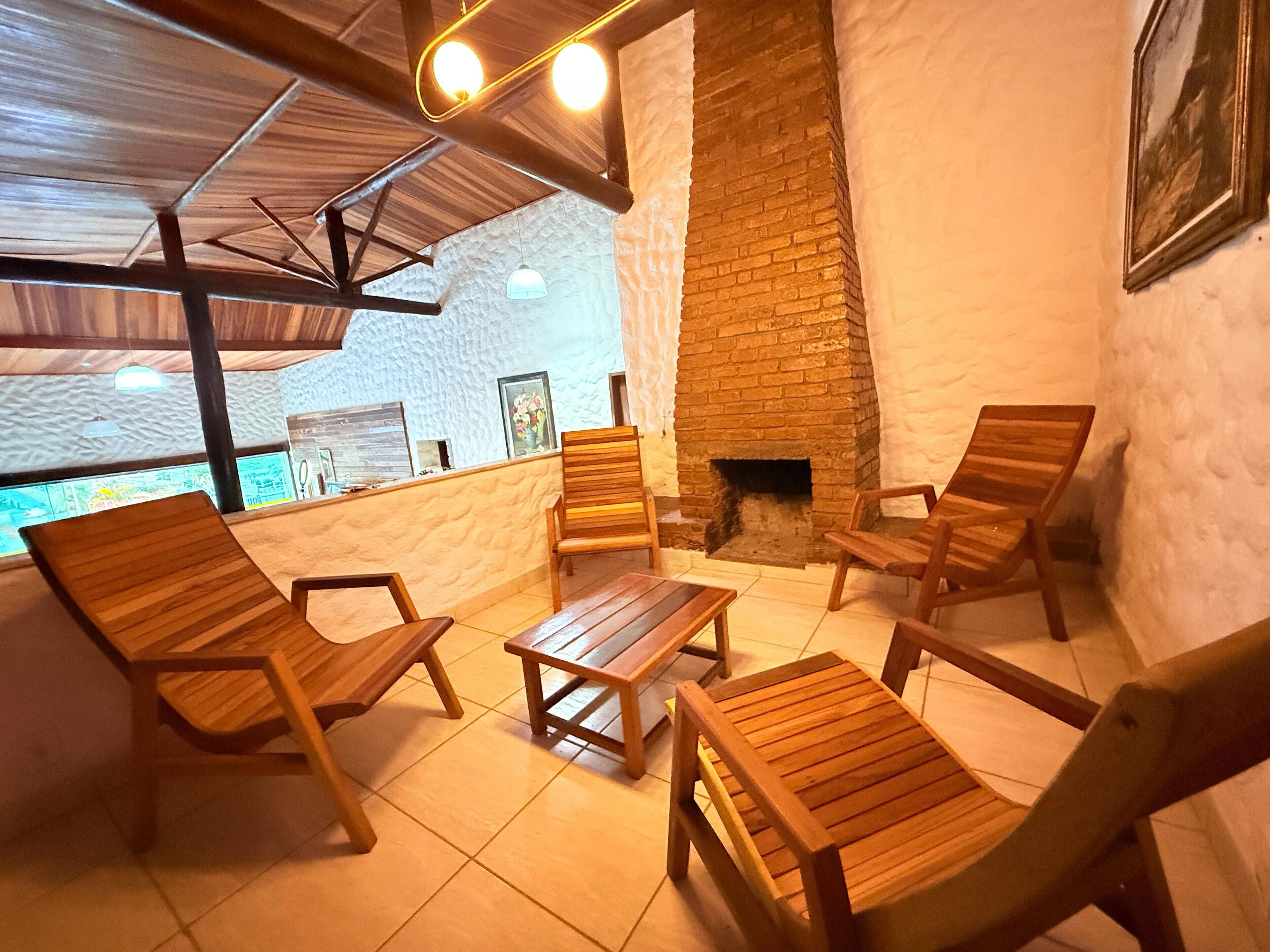 A cozy indoor seating area with wooden furniture, a brick fireplace, and a view of the outdoors.