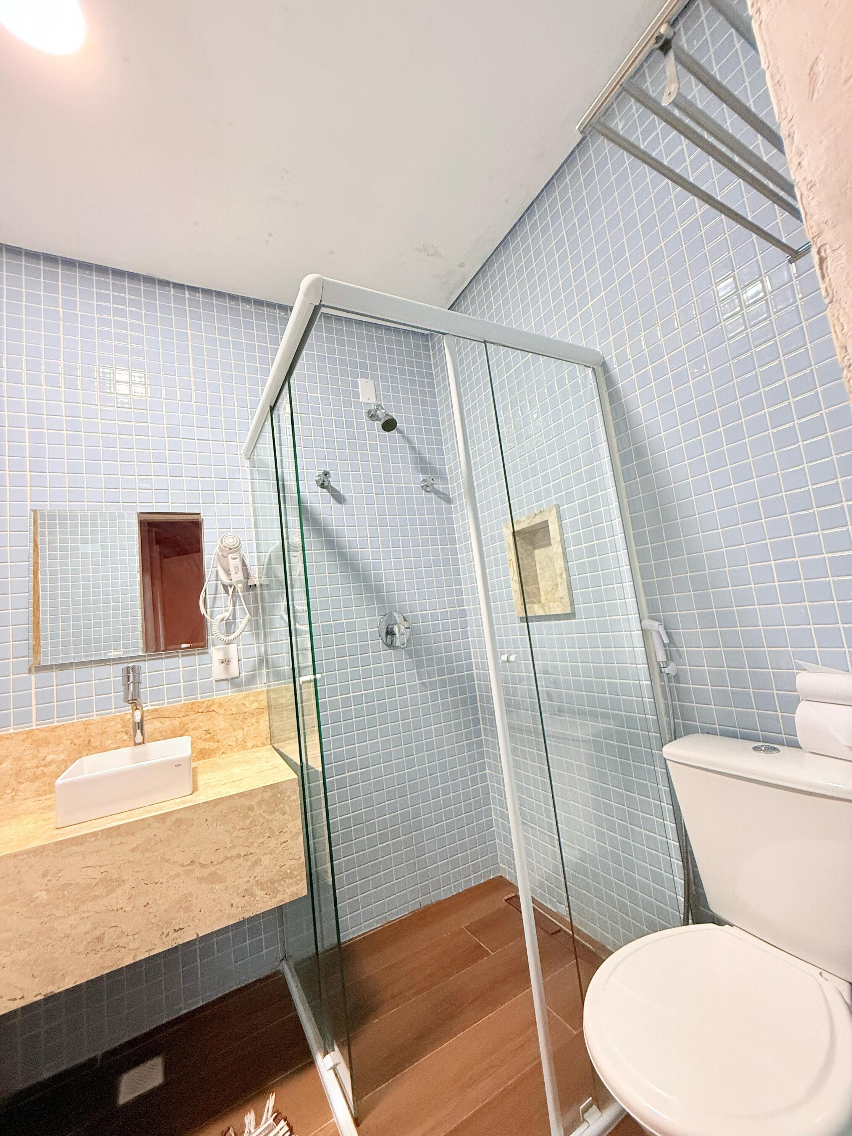Ein Badezimmer mit Duschkabine aus Glas, Waschbecken mit Spiegel und Toilette.