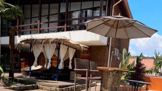 A hot tub in a wooden frame with a pool in the background.