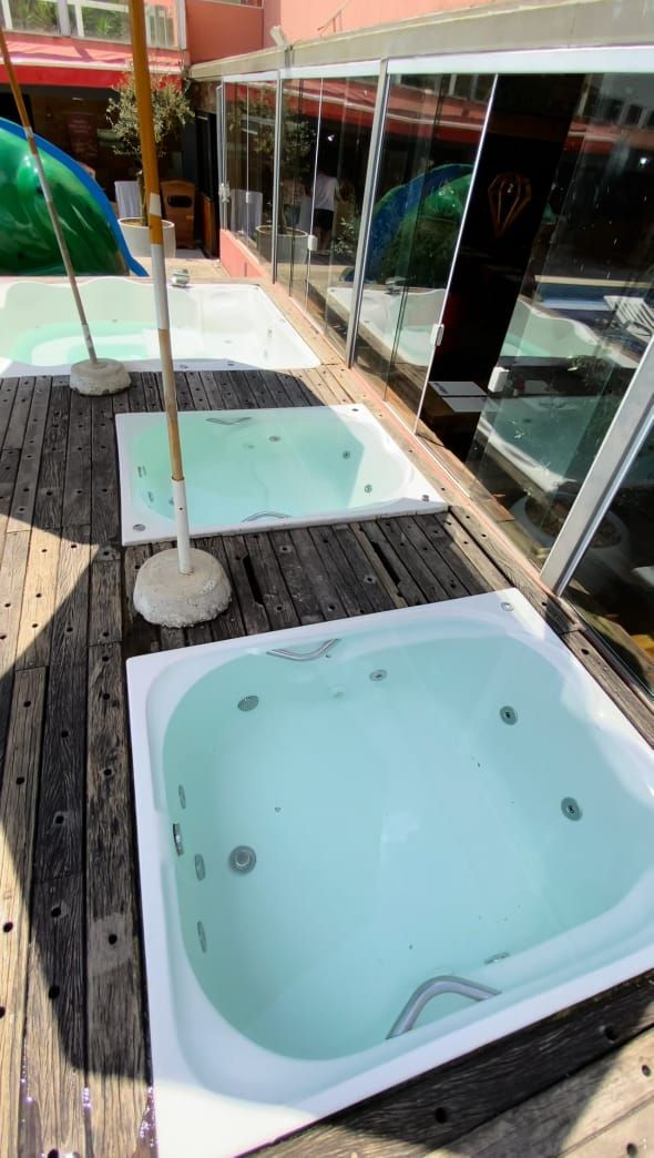 Une terrasse en bois avec deux bains à remous et un espace clos par des parois de verre.