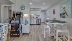 A modern kitchen with white cabinets, a stainless steel dishwasher, and a dining area with white stools.