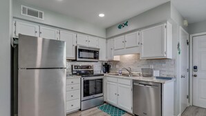 A modern kitchen with stainless steel appliances, white cabinets, a microwave, a stove, and a dishwasher.