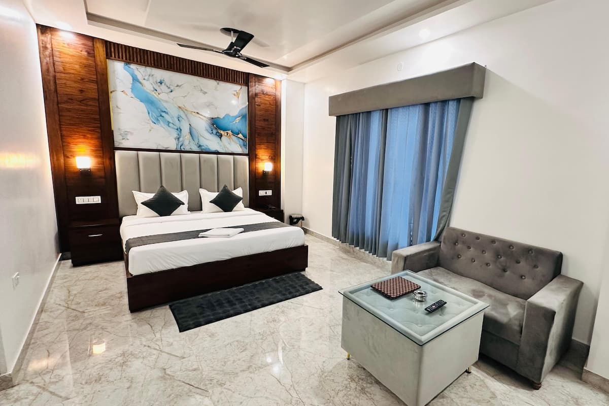 Una habitación de hotel moderna con una cama grande, un sofá, una mesa de centro de vidrio y un piso de mármol.