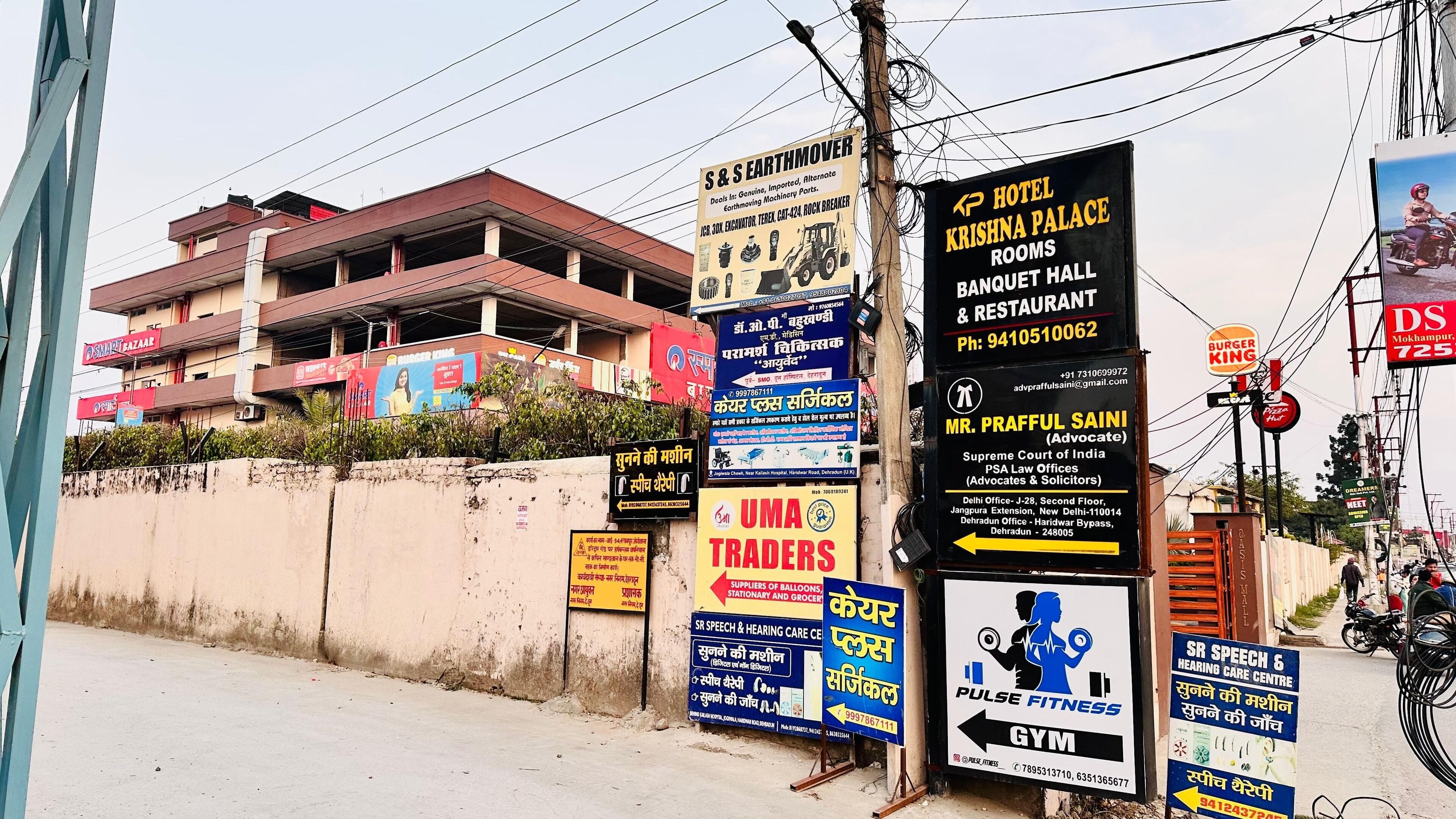 A street with various commercial signs, including a hotel, a restaurant, and a gym.