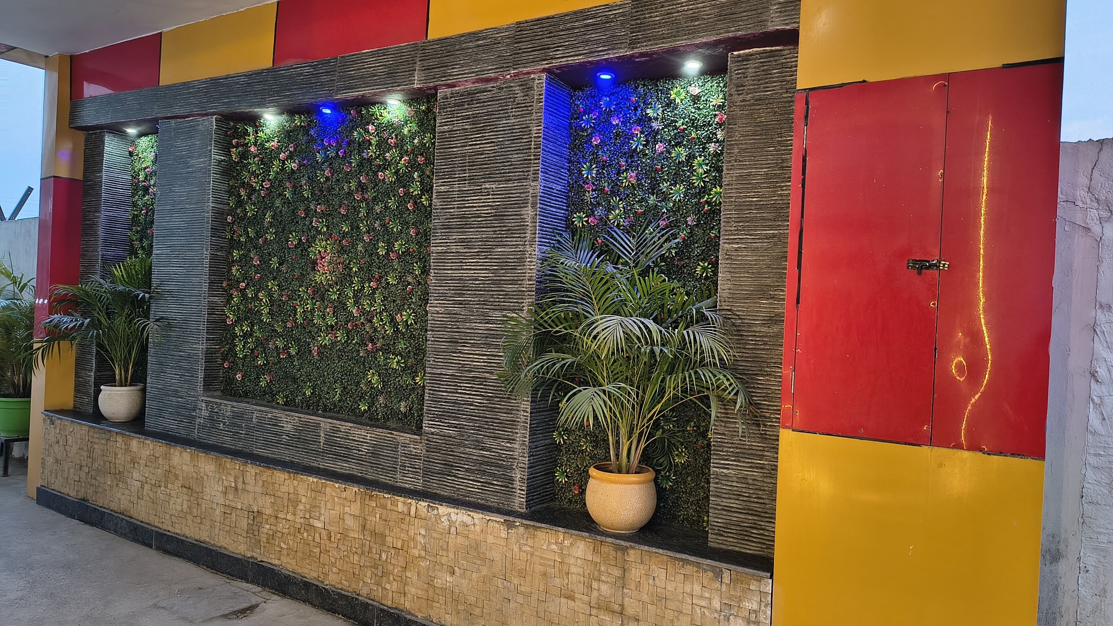 Un mur composé de panneaux verticaux, chacun contenant des plantes et éclairé par des lumières bleues.
