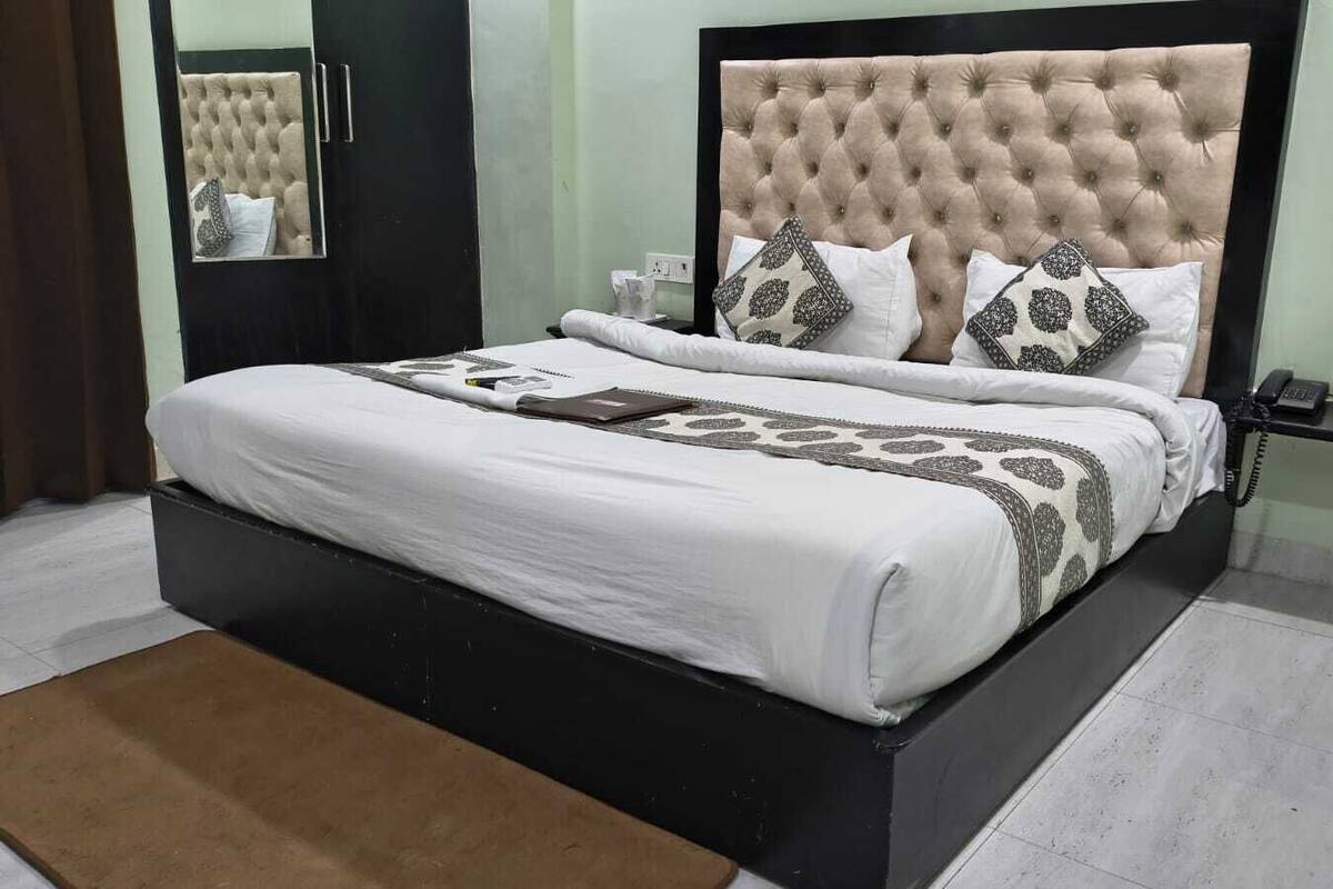 Una cama bien hecha con un cabecero capitonado, ropa de cama blanca y almohadones decorativos.