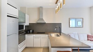 Una cucina moderna con isola centrale, elettrodomestici integrati e illuminazione a sospensione.