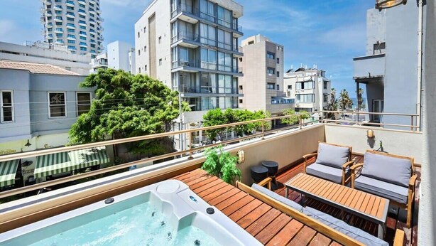 Una terrazza sul tetto con vasca idromassaggio, decking in legno e area salotto all'aperto.