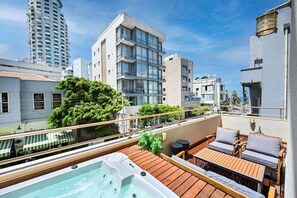 A rooftop terrace with a hot tub, wooden deck, and outdoor seating.