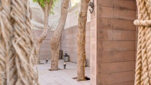 A modern outdoor area with wooden flooring, a stone wall, and a rope barrier.