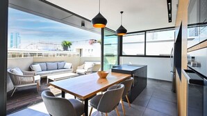 A modern kitchen with a dining area, large windows, and a view of the cityscape.
