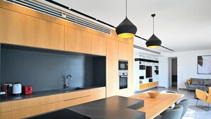 A modern kitchen with wooden cabinets, a black countertop, and a built-in oven. There is a dining area with a wooden table and chairs.