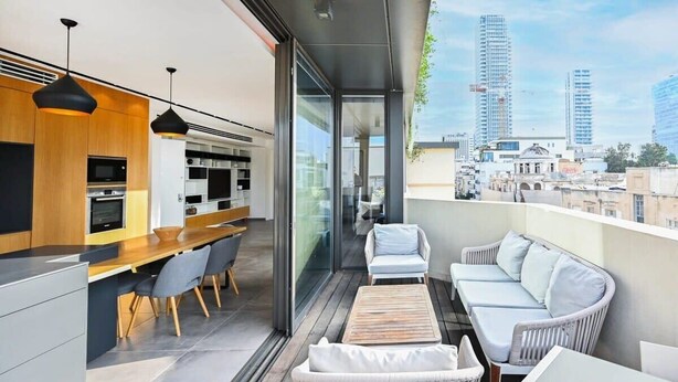 A modern apartment with a kitchen, dining area, and a balcony with a city view.