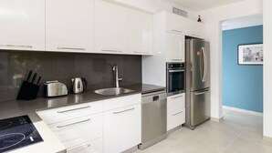 Een moderne keuken met witte kasten, roestvrijstalen apparatuur en een vaatwasser.