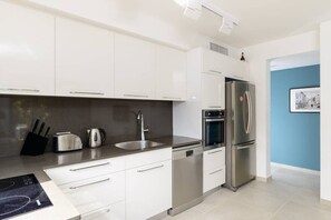 Una cocina moderna con armarios blancos, electrodomésticos de acero inoxidable y lavavajillas.