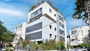 Un immeuble moderne à plusieurs étages, doté d’un toit plat, de grandes fenêtres et d’une entrée de garage bien visible.