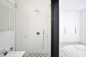 A modern bathroom with a glass-enclosed shower, a white sink, and a large mirror. - Tranquility 2BR at Trumpeldor by HolyGuest (Tel Aviv-Yafo)