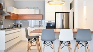 Une cuisine moderne avec des meubles blancs, un réfrigérateur en acier inoxydable et un îlot central doté de tabourets de bar.