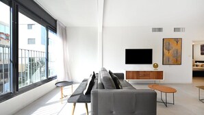 Un salon moderne avec un canapé gris, un téléviseur à écran plat et un meuble en bois.