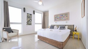Une chambre à coucher avec un grand lit, une chaise, une petite table et un ventilateur de plafond.