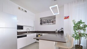 Une cuisine moderne avec des meubles blancs, un îlot central et un four à micro-ondes.