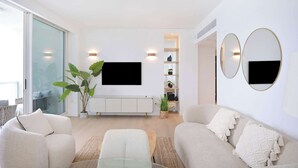 Een moderne woonkamer met een bank, een salontafel en een aan de muur bevestigde televisie.