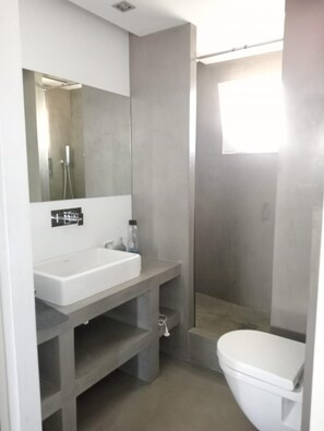 A modern bathroom with a white sink, mirror, and toilet.