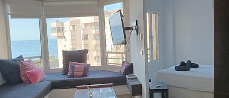 Una sala moderna con un sofá, una mesita de madera y una cama.