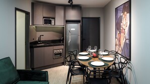 Una cucina funzionale con elettrodomestici moderni, una zona pranzo con tavolo imbandito per quattro persone e un'ampia opera d'arte incorniciata a parete.