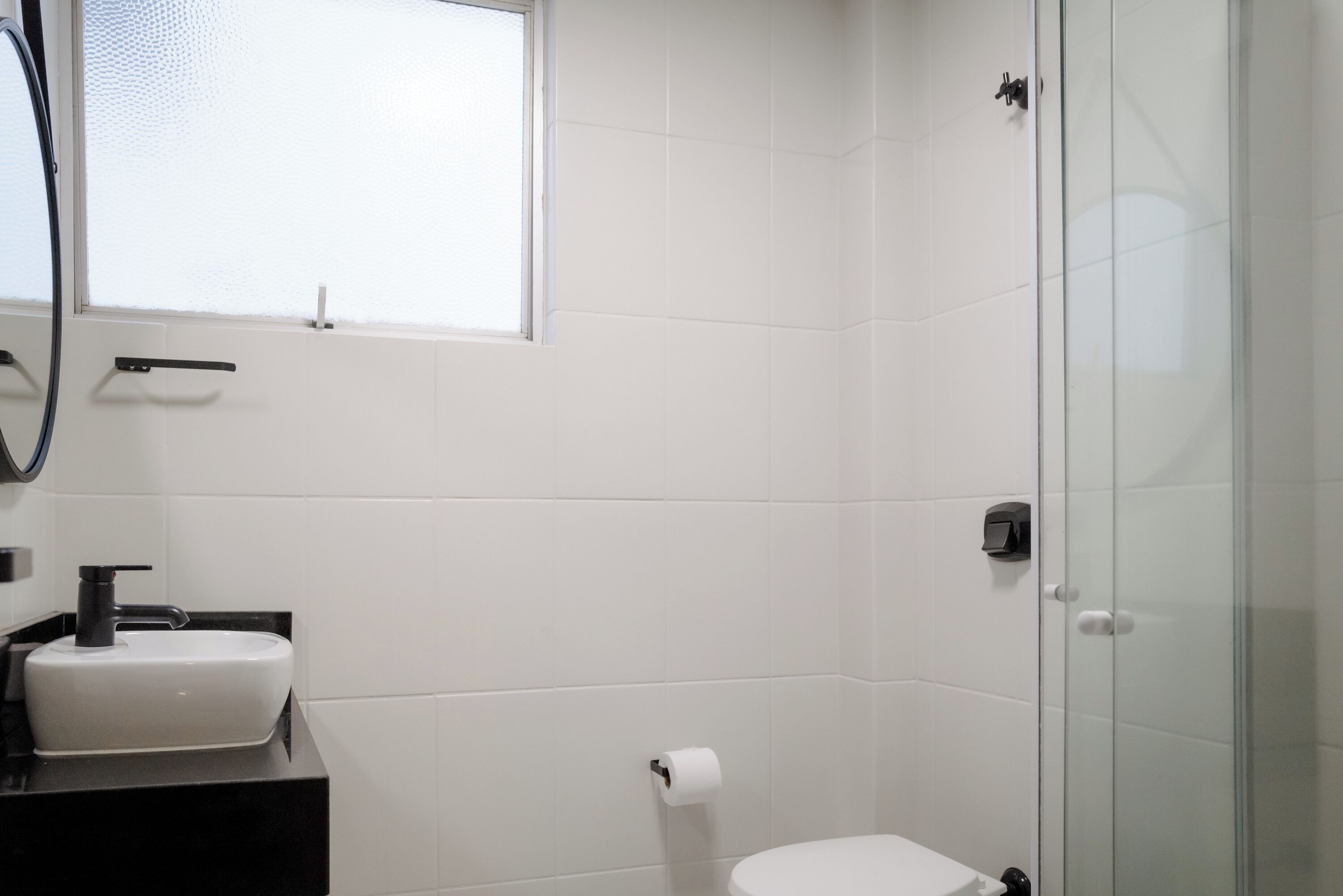 A bathroom with a white sink, toilet, and glass shower enclosure.