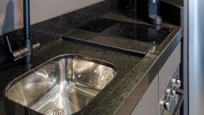 Una cucina moderna con forno a microonde integrato, lavello in acciaio inossidabile e un piano di lavoro elegante.