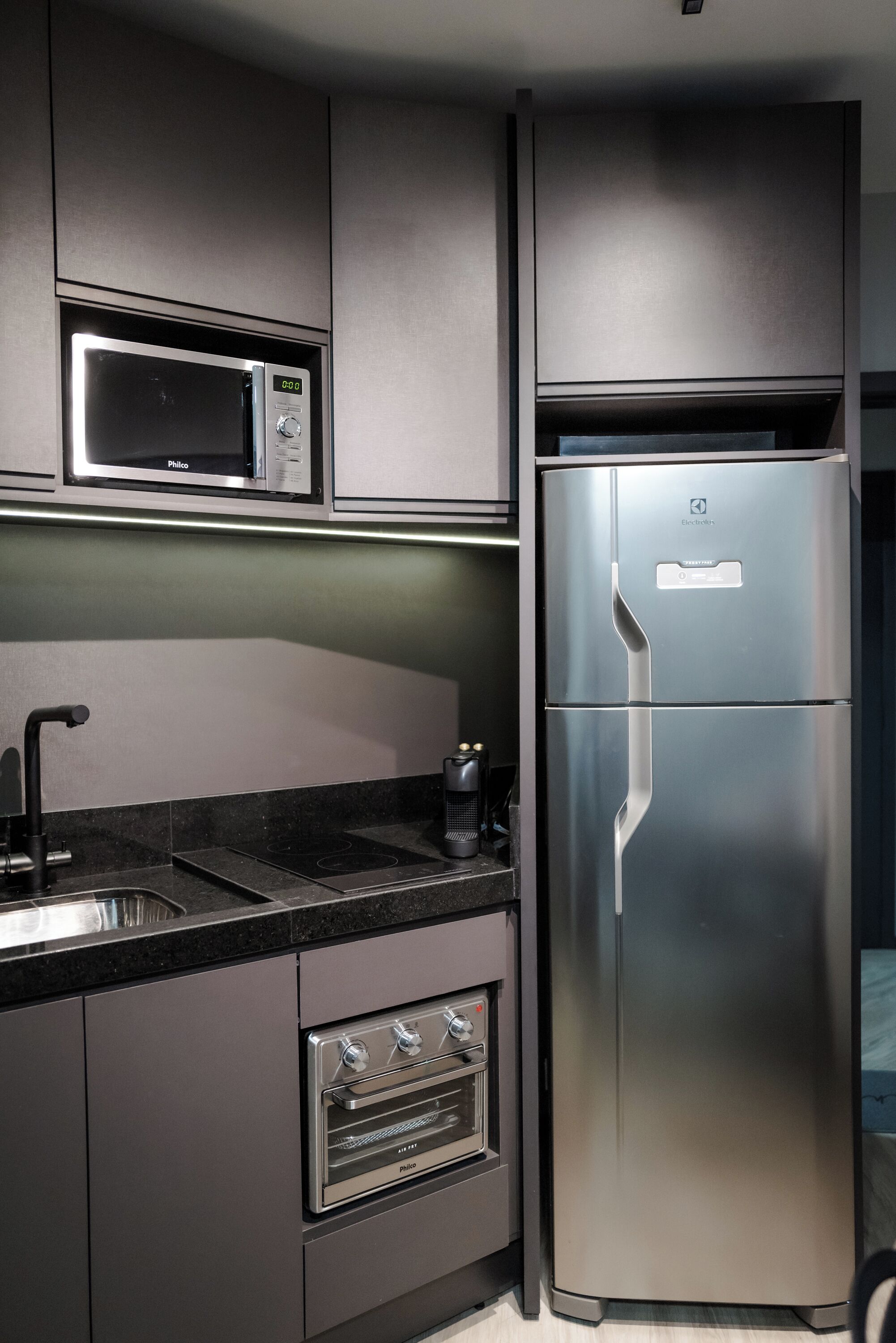 A modern kitchen with a stainless steel refrigerator, built-in microwave, and oven.