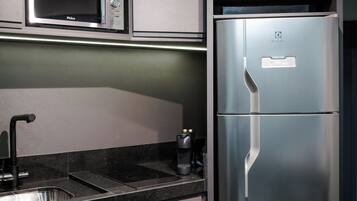 A modern kitchen with a stainless steel refrigerator, built-in microwave, and oven.