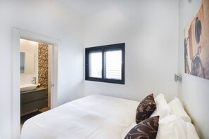A bedroom with a bed, a window, a bathroom with a sink, and a wall-mounted picture. - Zebra's Stripe by HolyGuest (Tel Aviv)