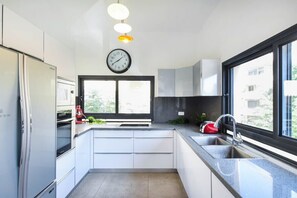 A modern kitchen with white cabinetry, a built-in oven, a sink, and a window providing natural light.