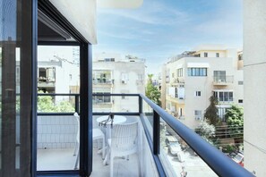 A balcony with a table and chairs, overlooking a residential area with multiple buildings.
